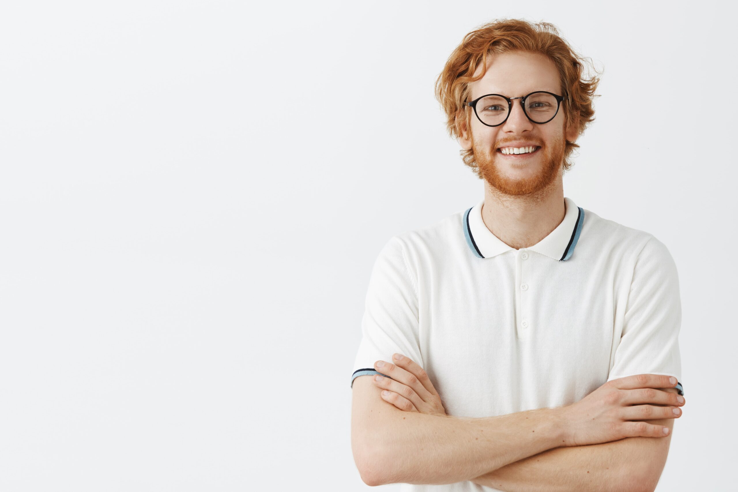 handsome bearded redhead guy posing against white wall with glasses min scaled