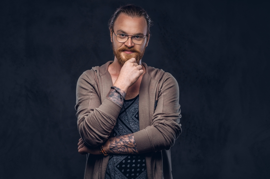 smart pensive redhead hipster with full beard glasses dressed casual clothes poses with hand chin studio isolated dark background
