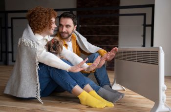 full-shot-couple-warming-up-their-hands-with-heater_23-2149339545